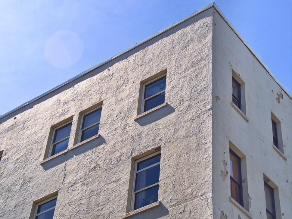 Free Image of Corner view of aged white building under bright sky. 