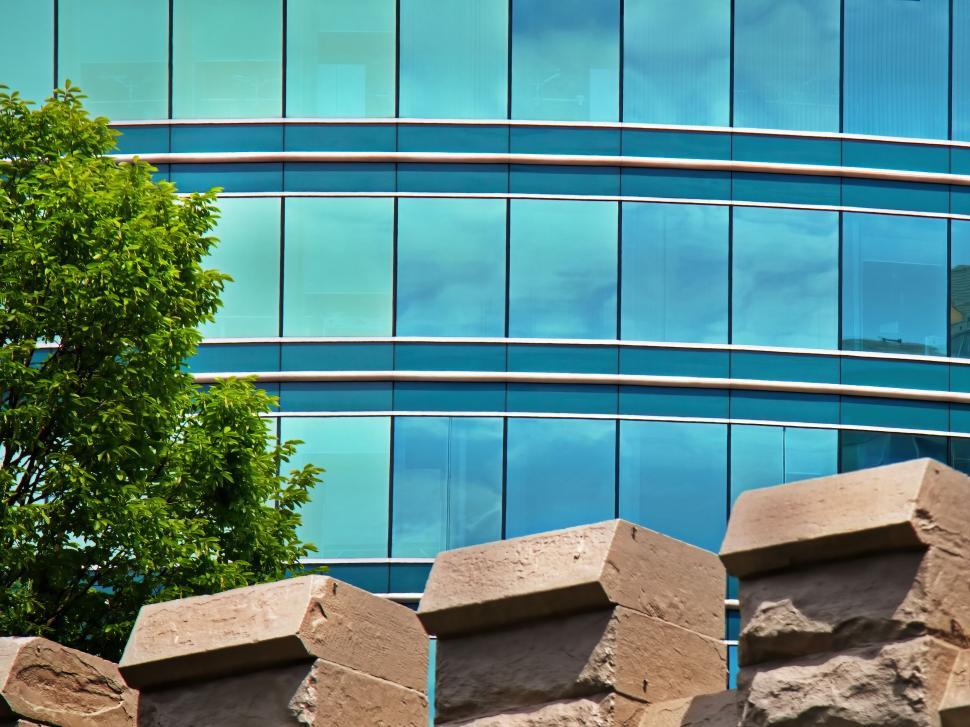 Free Image of Curved glass building with trees and brick wall view. 