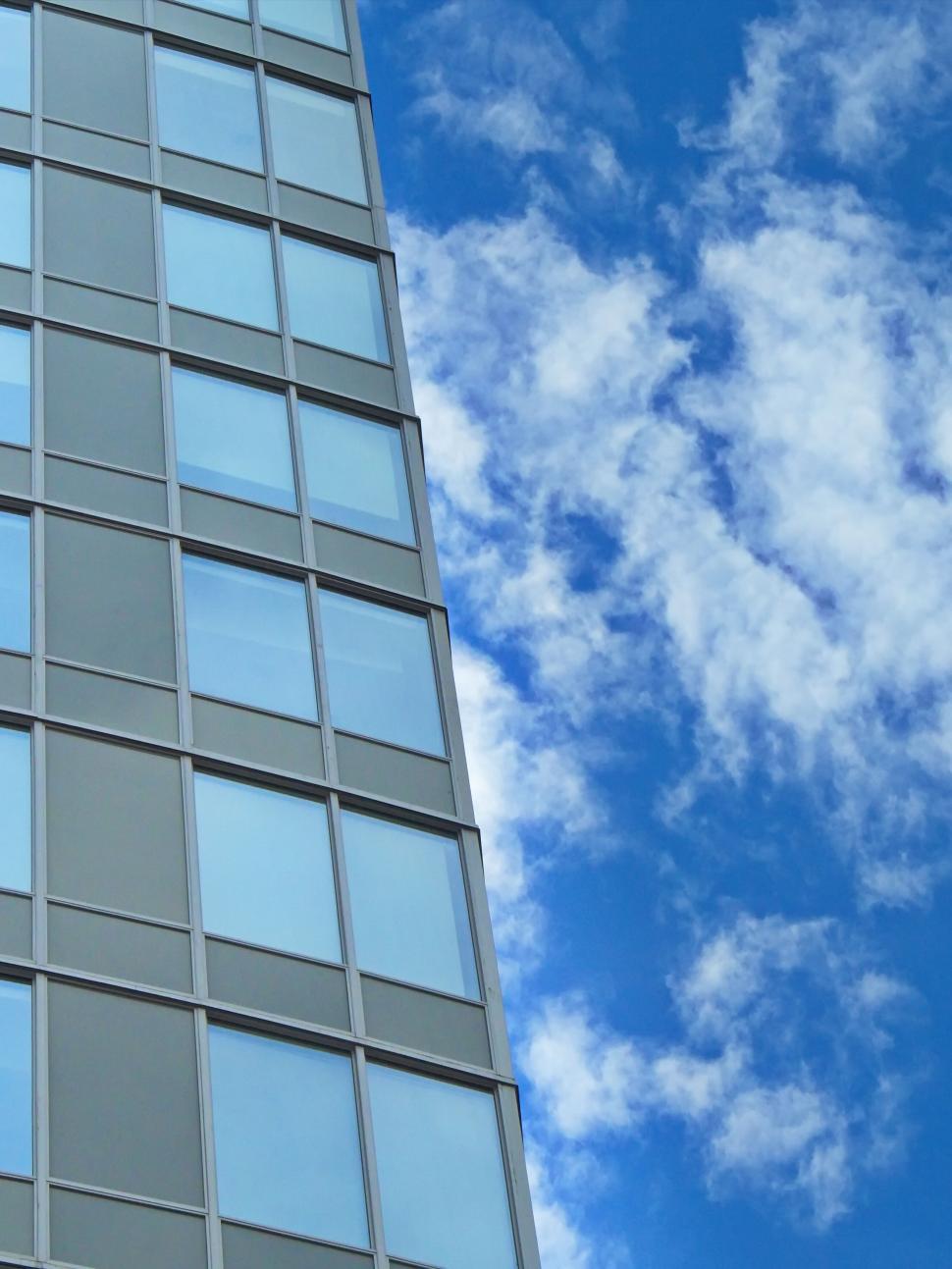 Free Image of Glass building facade reflecting a bright blue sky 
