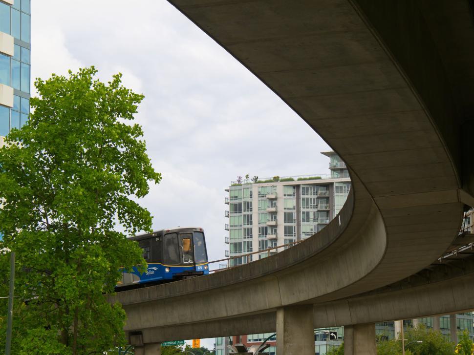 Free Image of Metro train on curved track with modern buildings backdrop 