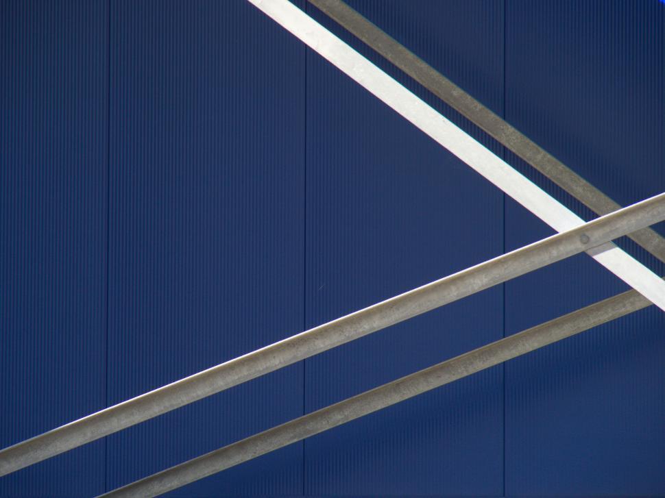 Free Image of Blue wall with intersecting metal beams, abstract design 