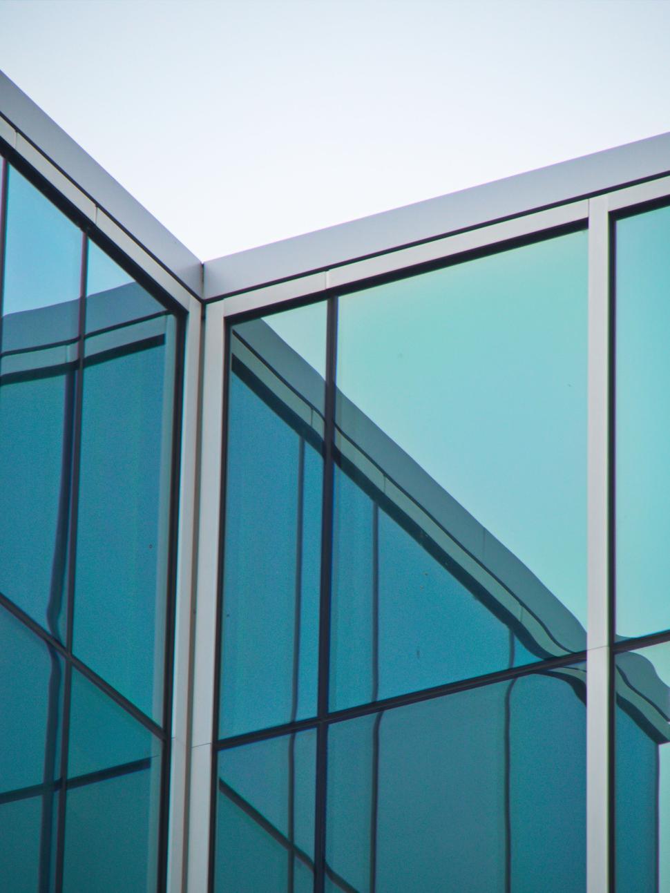 Free Image of Modern glass building corner with reflections, blue hue 