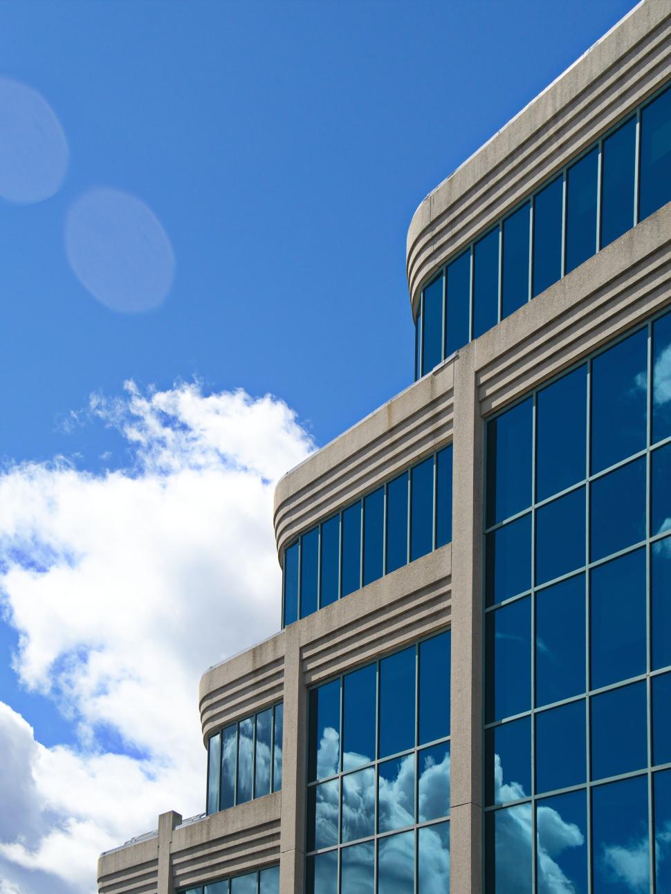 Free Image of Modern glass building reflecting blue sky and clouds 
