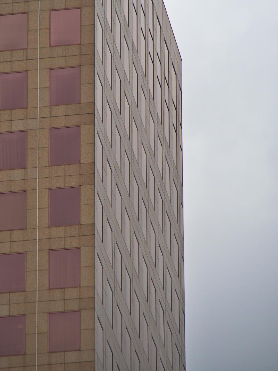 Free Image of Tall glass building with grid pattern and pink windows 