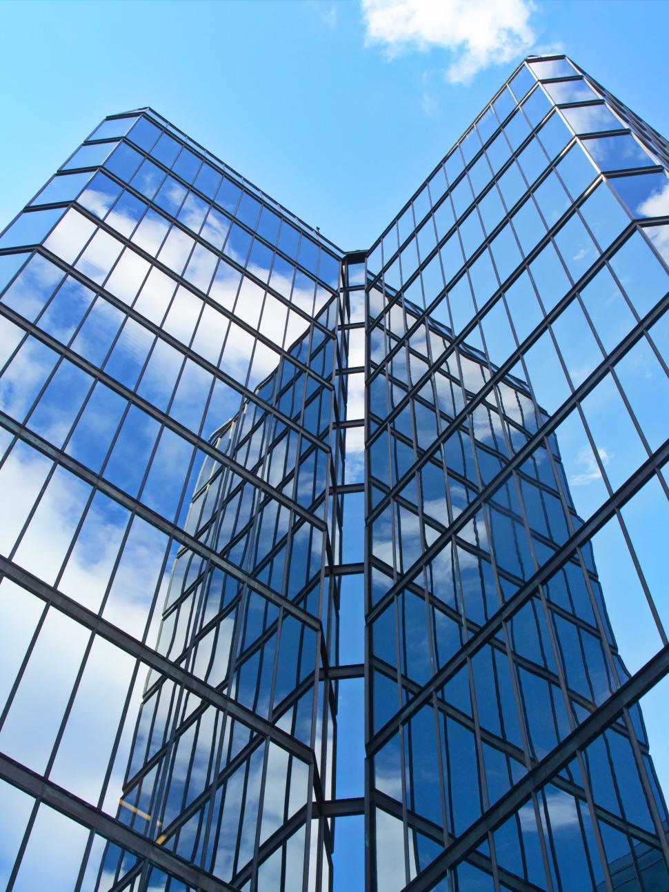 Free Image of Sharp-edged glass building with reflection of blue sky 