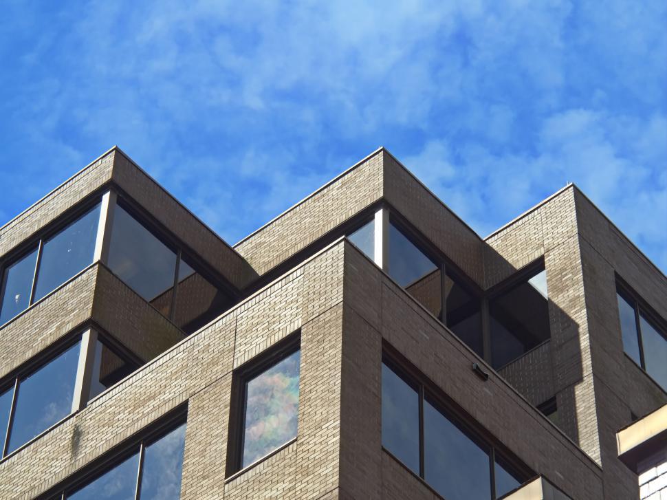 Free Image of Angular brick building with large windows under clear sky. 