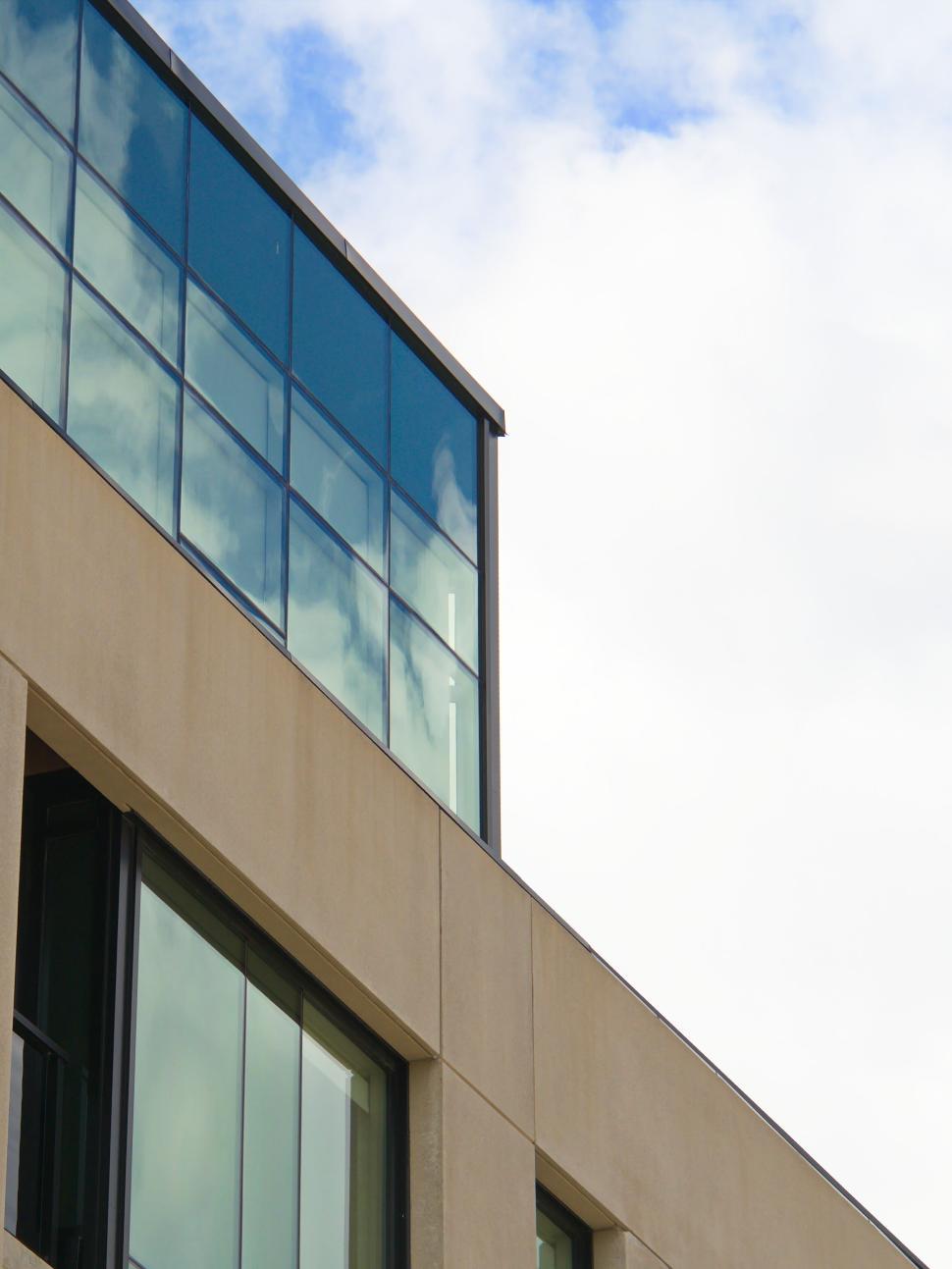 Free Image of Modern glass building against partly cloudy blue sky. 