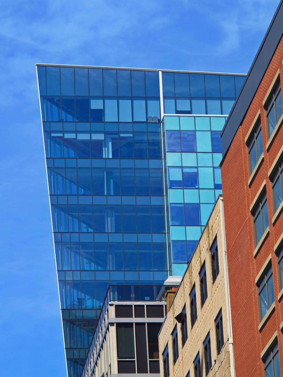 Free Image of Modern blue glass building against a clear blue sky 