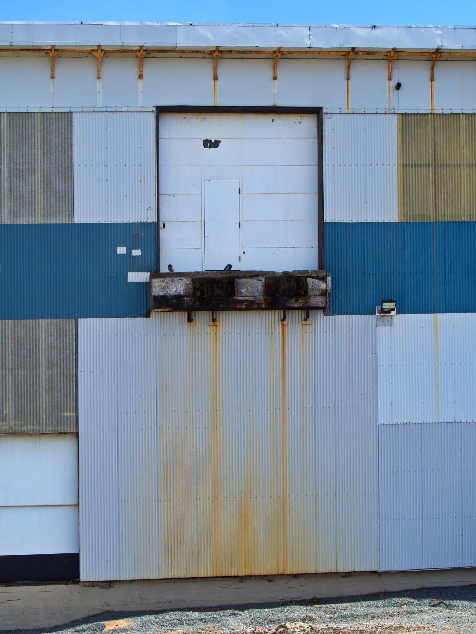 Free Image of Rusty industrial building with a closed door on the wall. 
