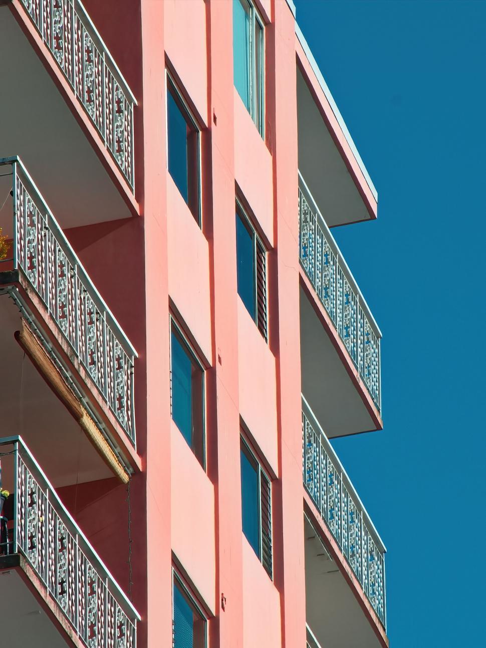 Free Image of Pink apartment building against clear blue sky backdrop. 
