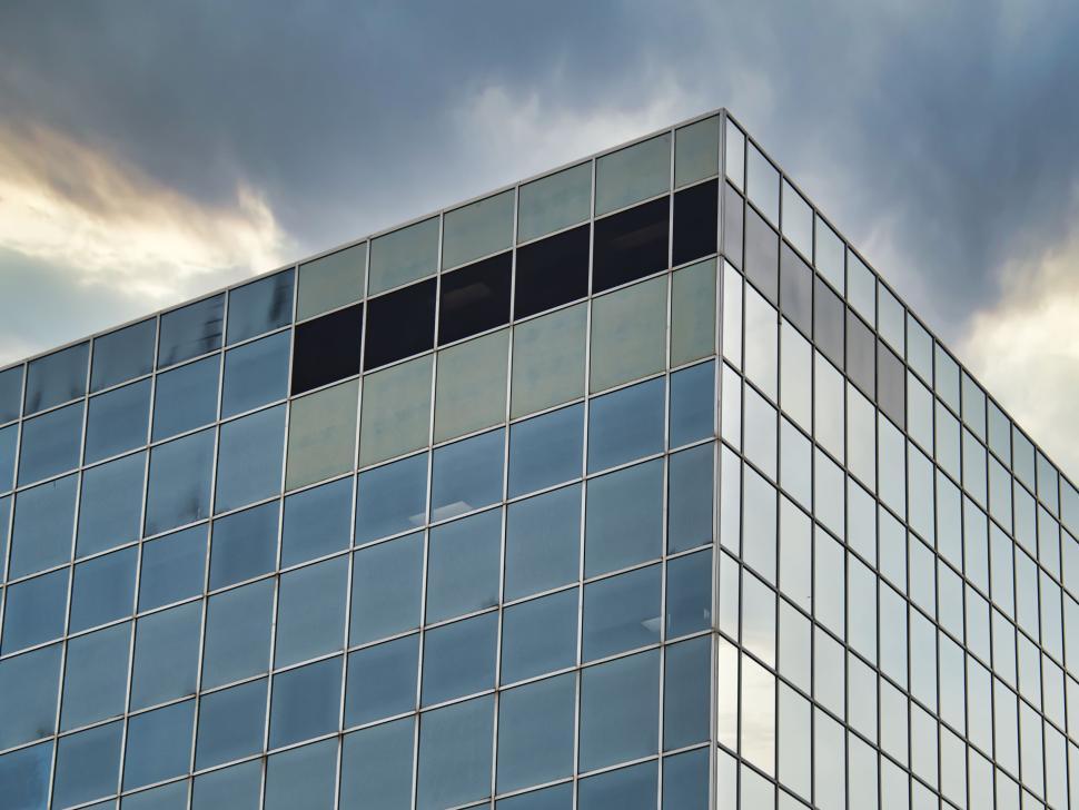 Free Image of Glass office building reflecting dramatic cloudy sky 