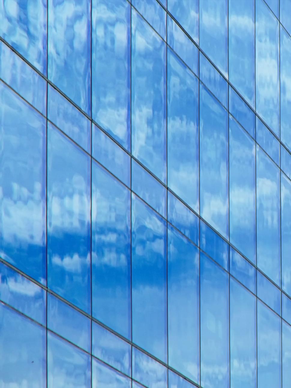 Free Image of Reflective blue glass building facade with sky reflections 
