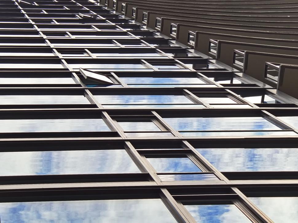 Free Image of Tall glass building with reflective windows and sky view 