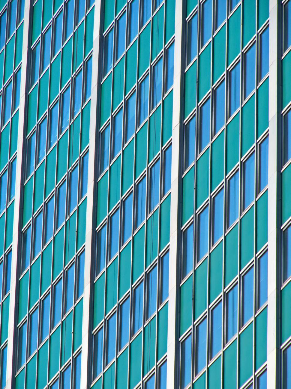 Free Image of Green glass building with diagonal window patterns 