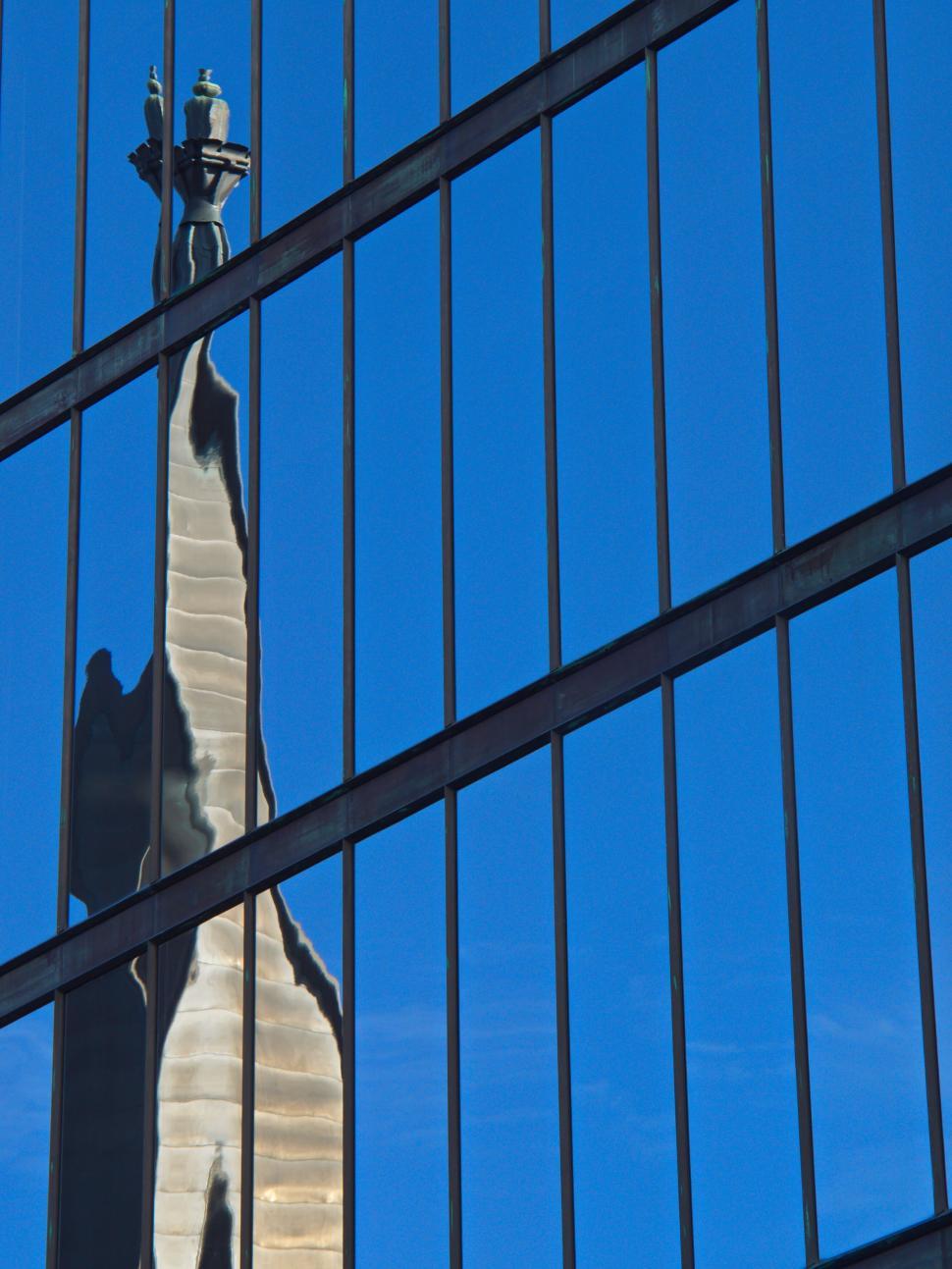 Free Image of Distorted monument reflection in tall glass building 