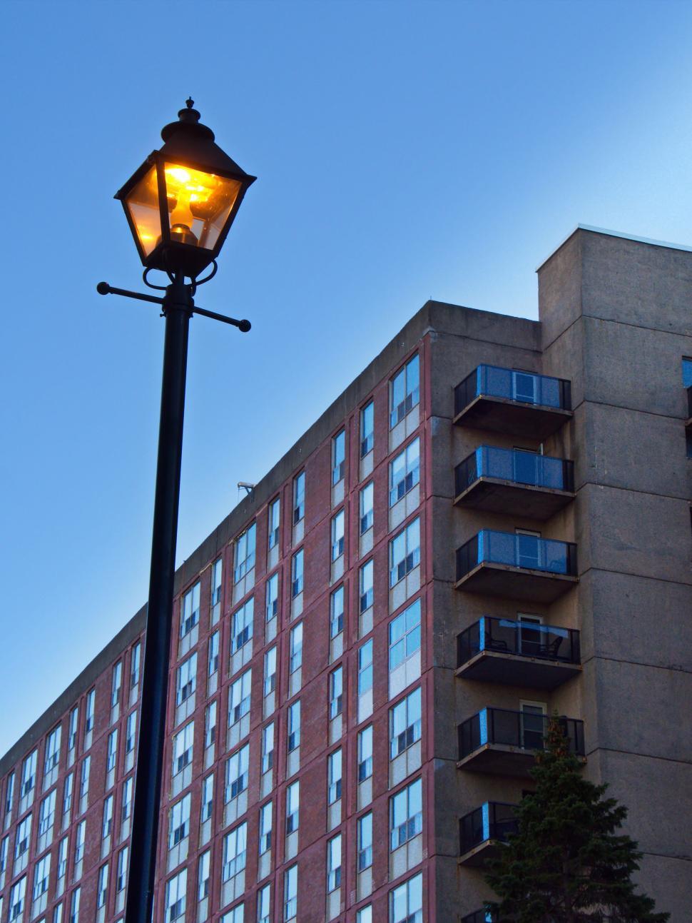 Free Image of Old-fashioned street lamp glowing against apartment building. 