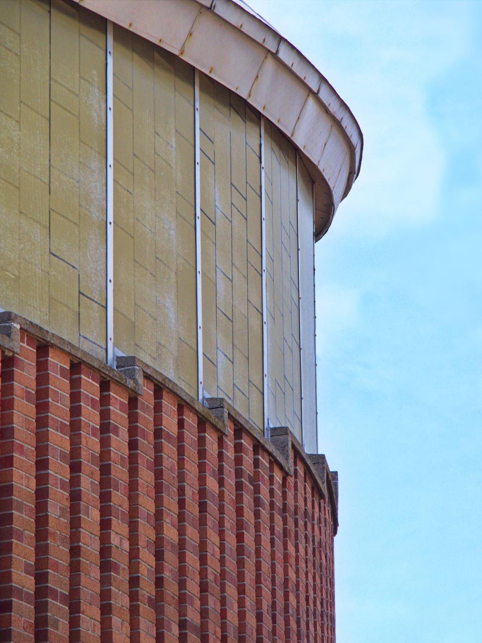 Free Image of Curved brick and yellow facade building with windows 
