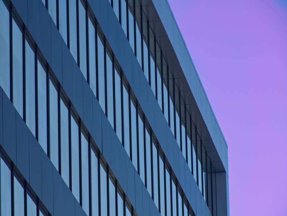 Free Image of Symmetrical office building windows with purple sky view 