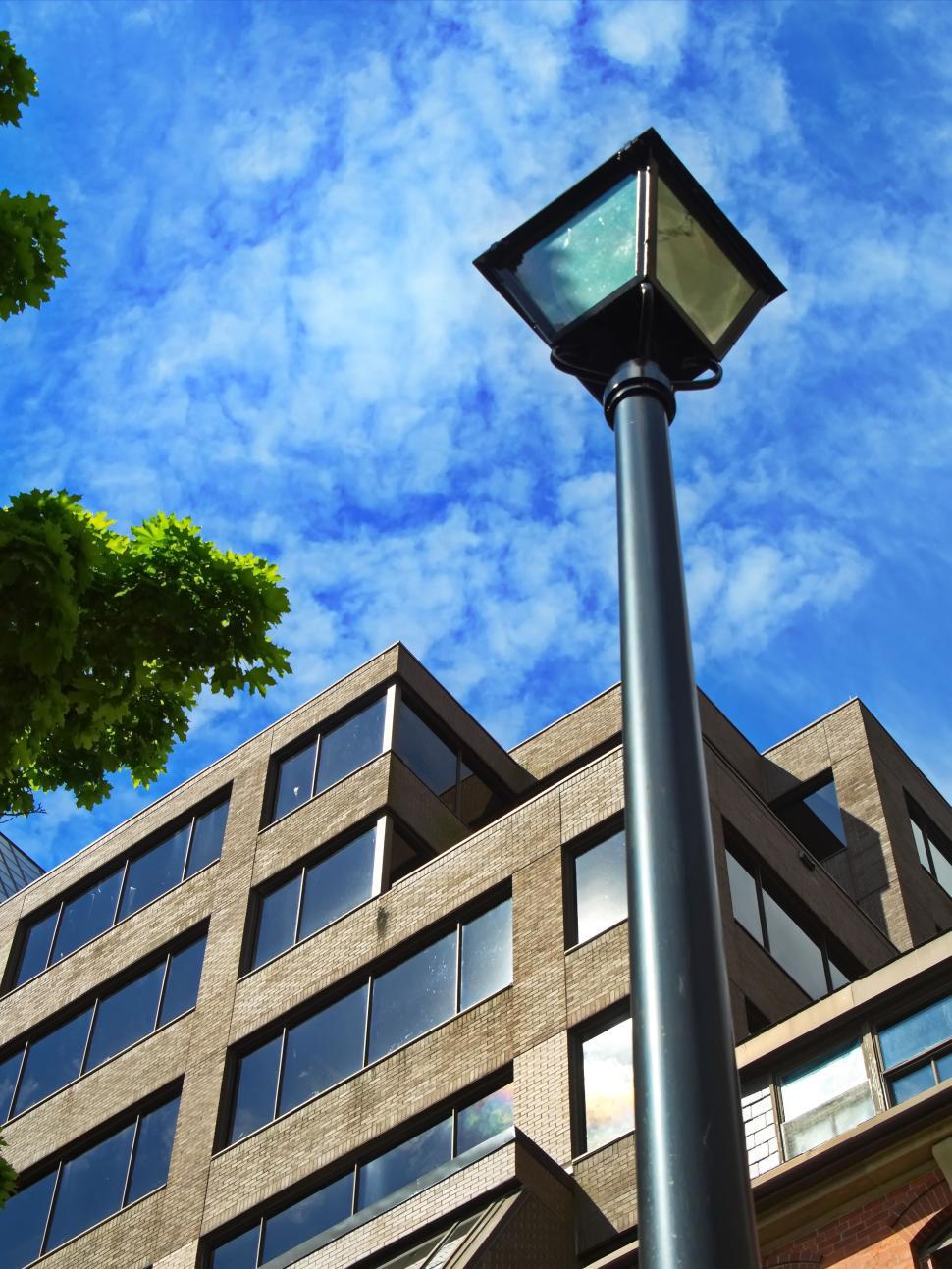 Free Image of Brick building with reflective windows and streetlight. 