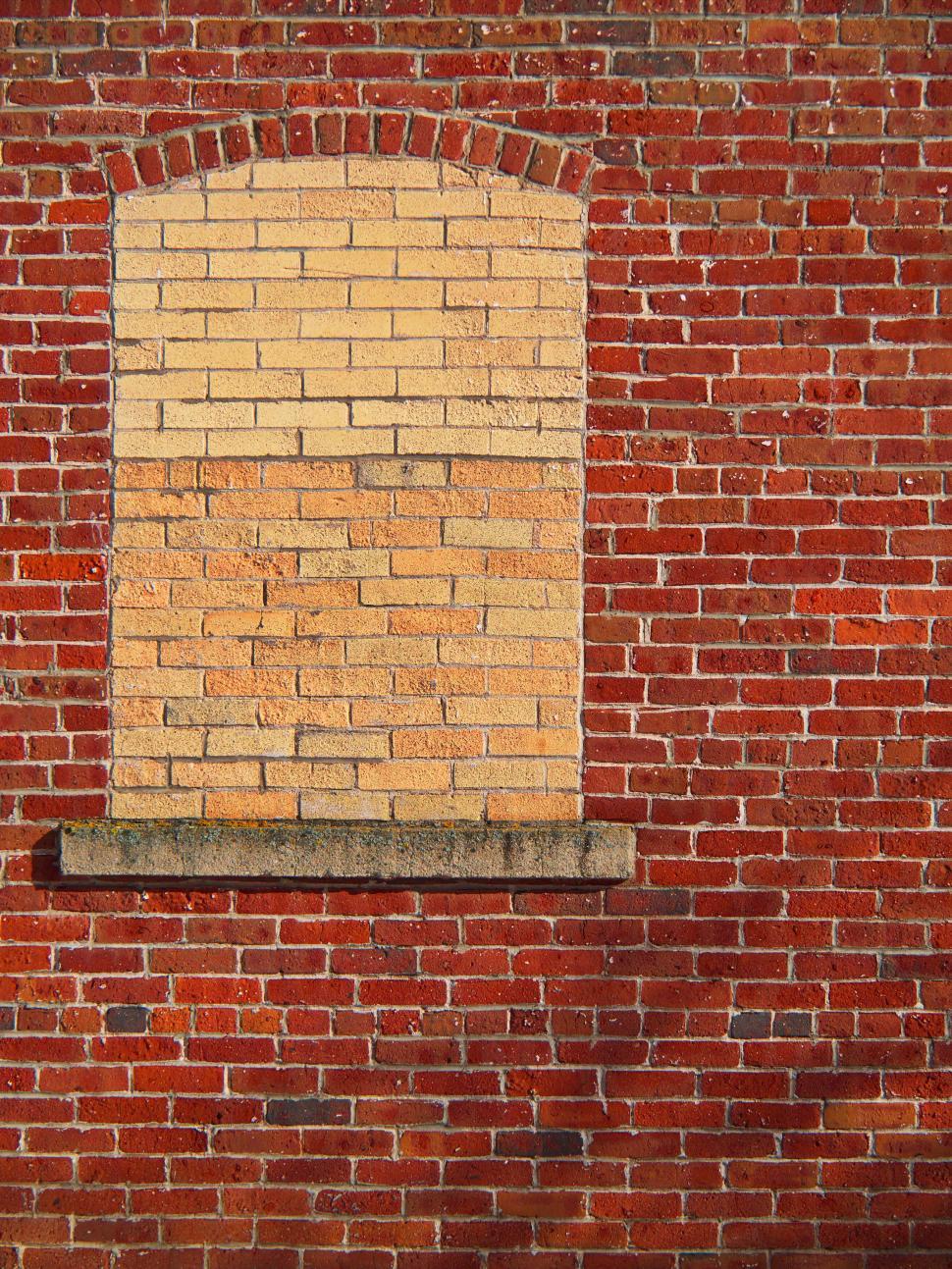 Free Image of Red brick wall with an old sealed archway window. 