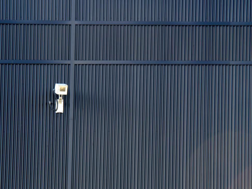 Free Image of Security camera mounted on a black ridged wall surface 