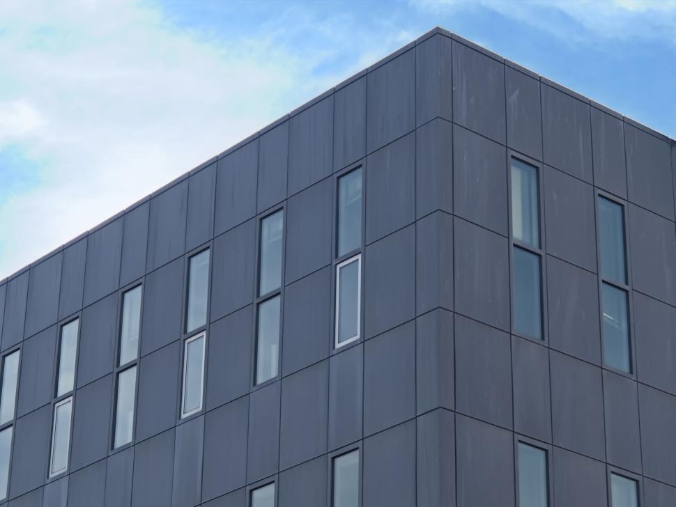 Free Image of Modern grey building with tall windows and blue sky 