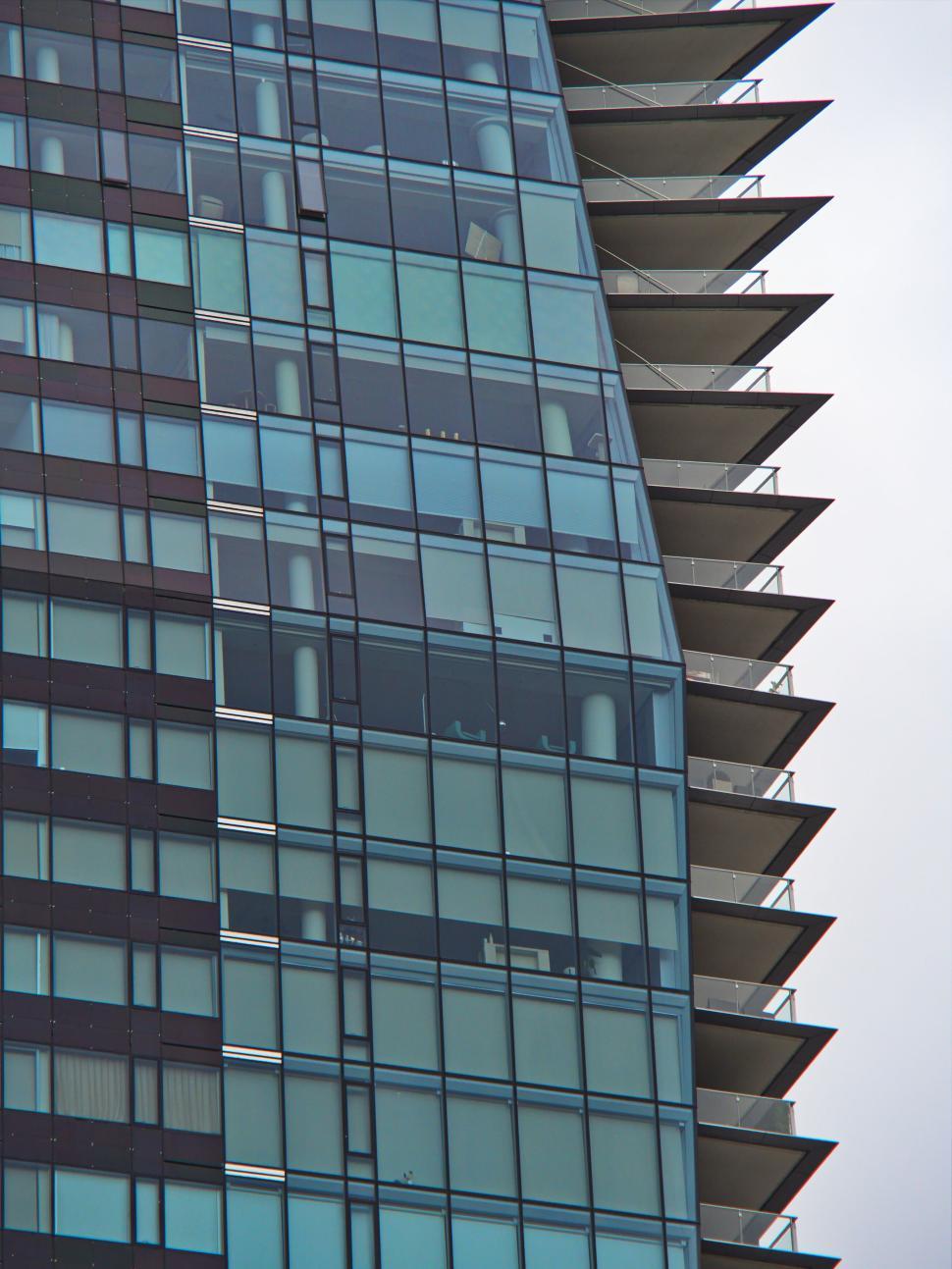 Free Image of Modern glass building with balconies on a cloudy day. 
