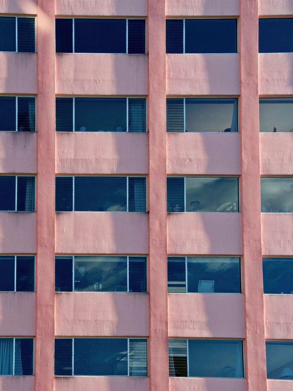 Free Image of Pastel pink building with multiple uniform windows. 