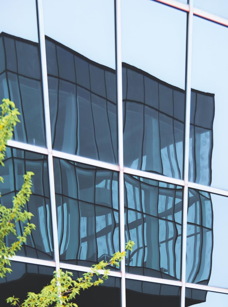 Free Image of Reflection of a wavy building on a glass facade 
