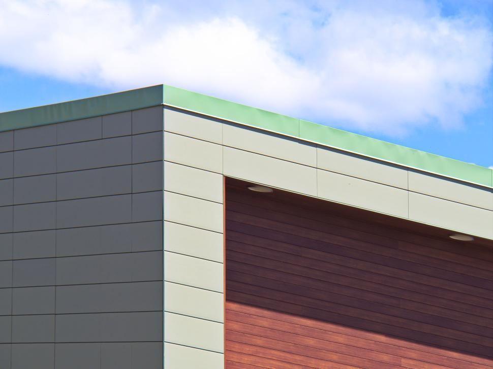 Free Image of Minimalist corner facade with green roof and blue sky 