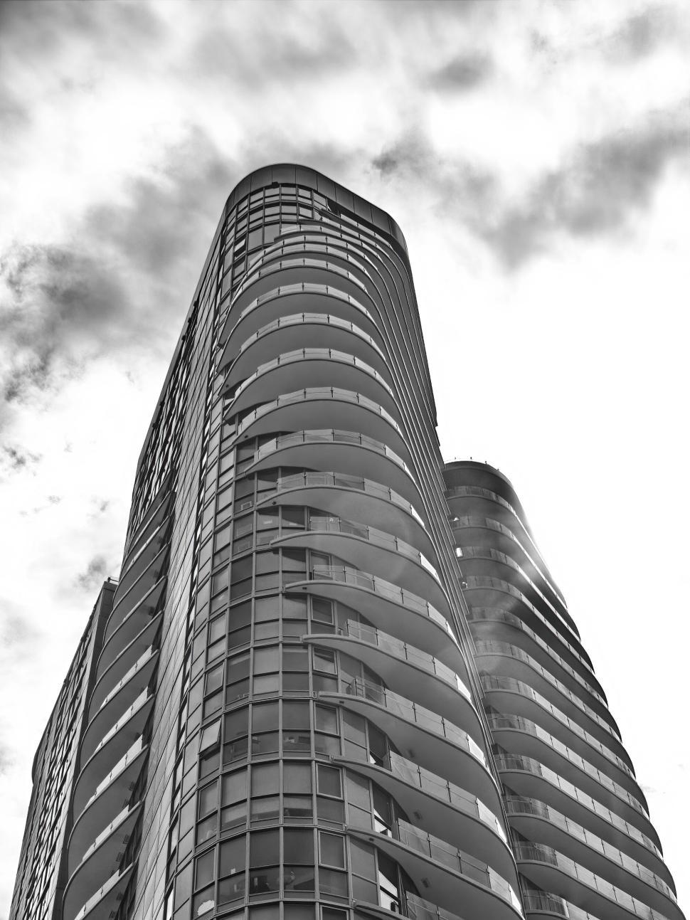 Free Image of Tall curved building in black and white reaching skyward 