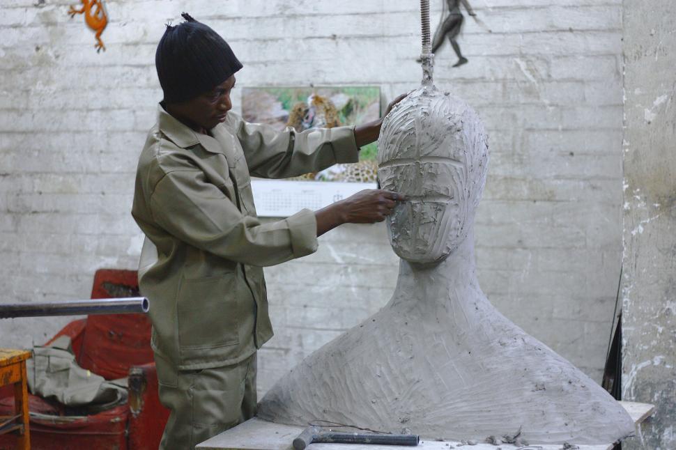 Free Image of Person sculpting a large clay bust in a workshop 