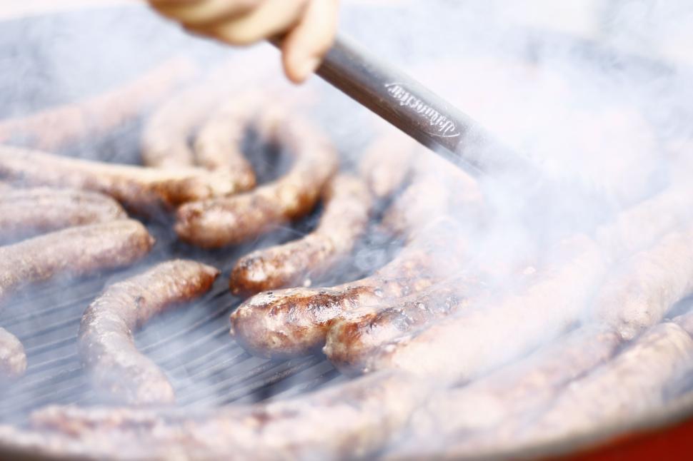 Free Image of Grilling sausages on a smoky barbecue with tongs 