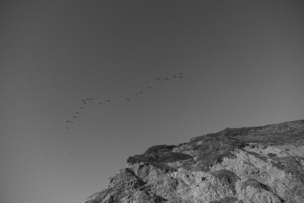 Free Image of Birds flying in V-formation over a mountain landscape 