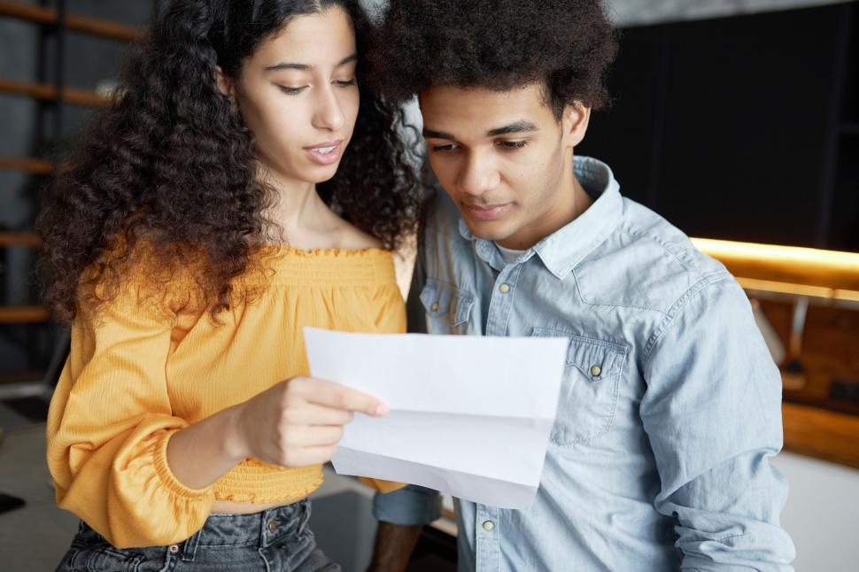 Free Image of Portrait of black young couple reading loan application together, discussing their expanses and budget, standing in loft kitchen, woman holding paper document and talking to her husband 