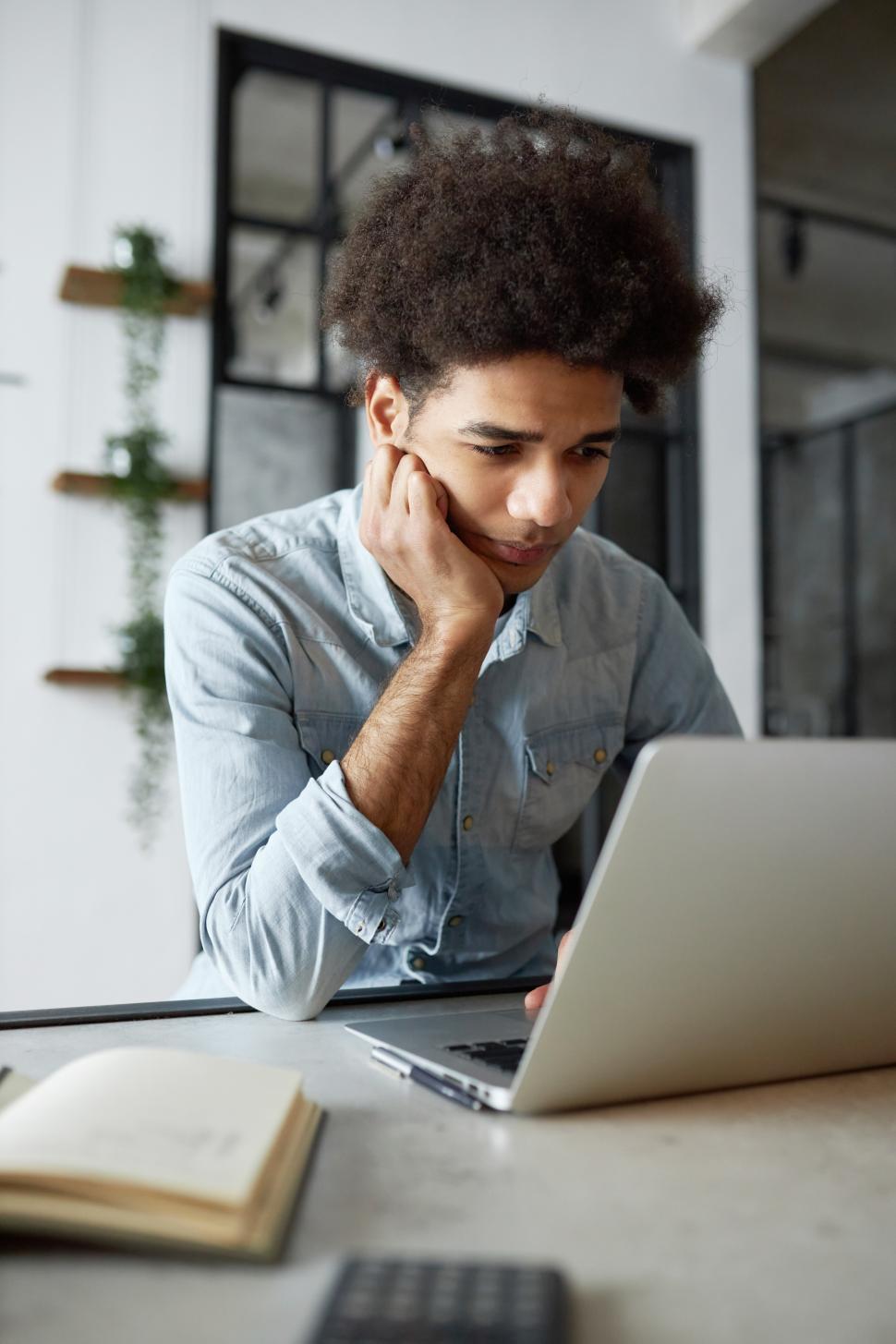 Free Image of Upset tired exhausted african american male student studying online sitting at table using laptop, finishing his thesis, making last corrections and edits. Remote education concept 