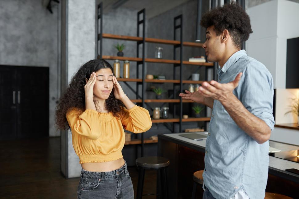 Free Image of Young black couple arguing and sorting things out, guy in denim shirt shrugging shoulders, explaining his opinion, while female standing with closed eyes and massaging temples, refusing to listen 