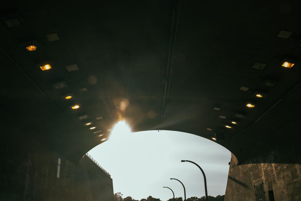 Free Image of Sunlight breaking through underpass with streetlights on 