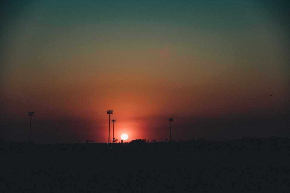 Free Image of Sunset over horizon silhouetted by stadium floodlights 