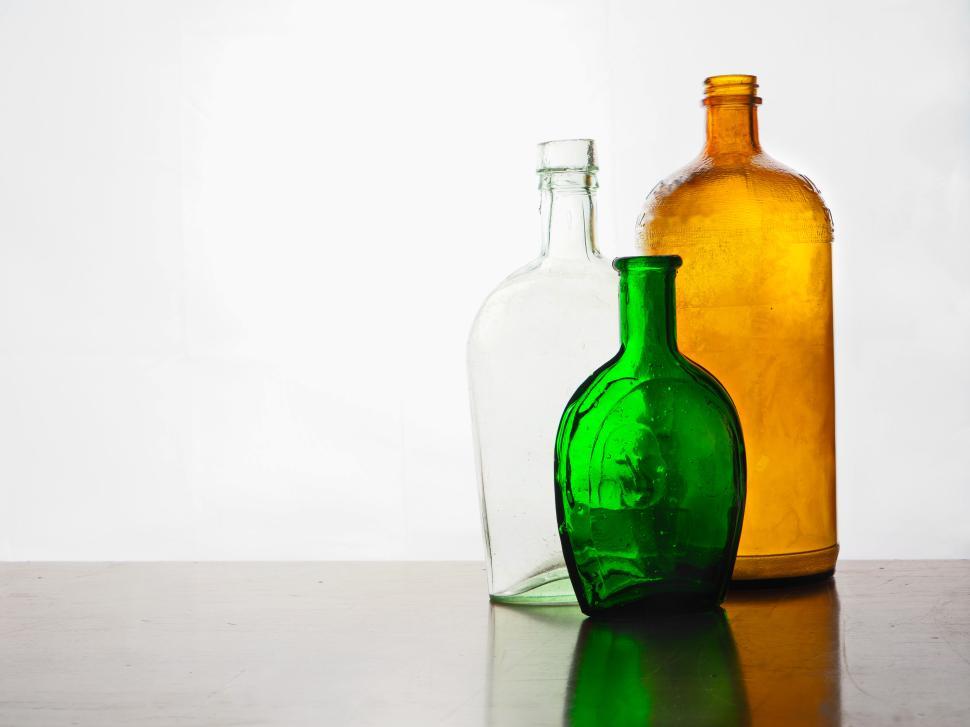 Free Image of Three colorful glass bottles arranged on a wooden surface. 