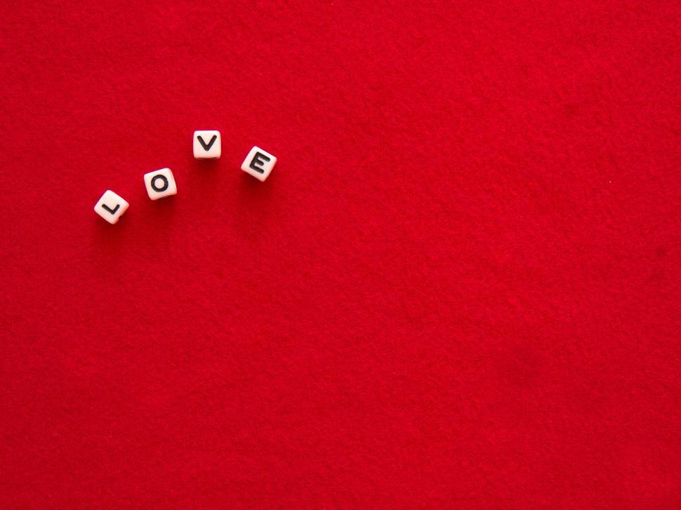 Free Image of Red background with  LOVE  spelled out in white cubes. 