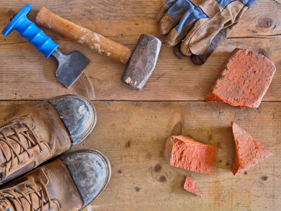 Free Image of Tools and bricks on a wooden surface, worn work boots 