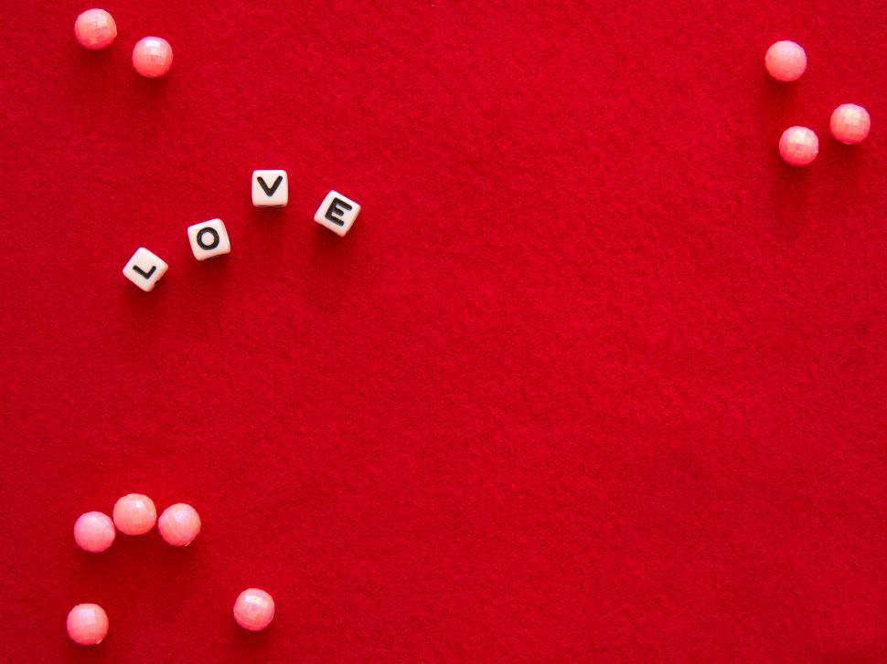 Free Image of Dice spelling out  LOVE  on red background with beads. 