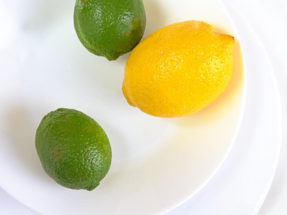 Free Image of Fresh lemon and limes setup on clean white plates. 