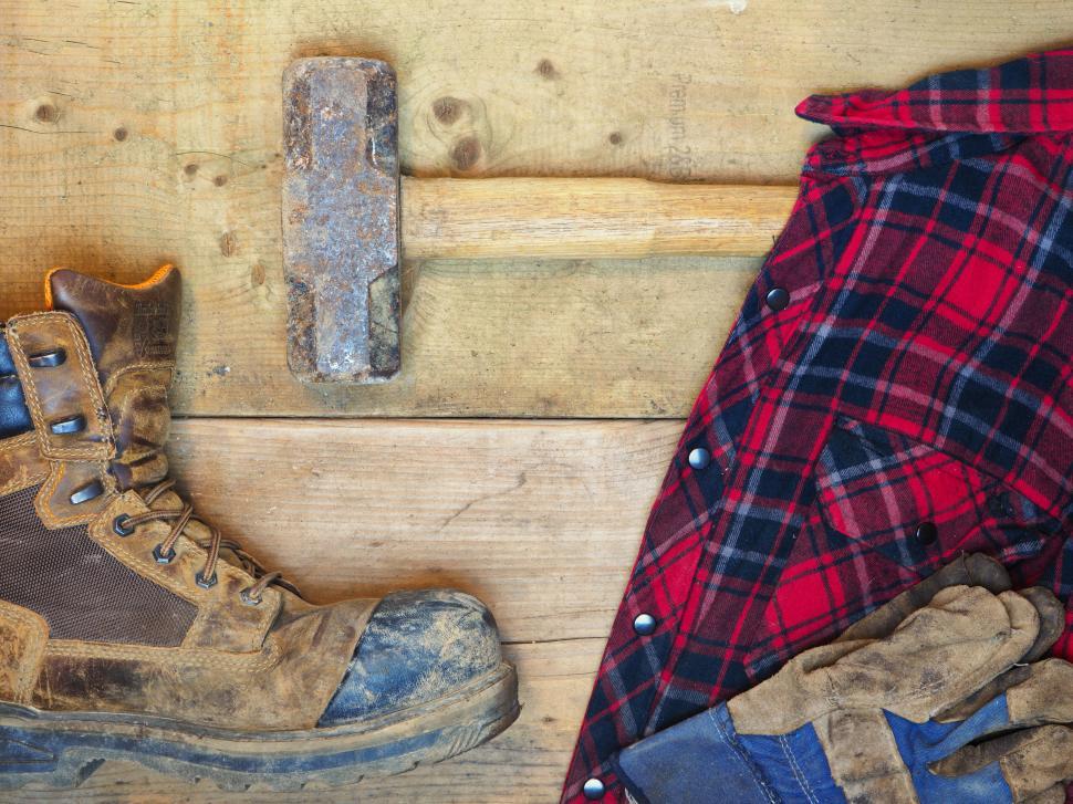 Free Image of Worn work boots, hammer and plaid shirt on wooden table 