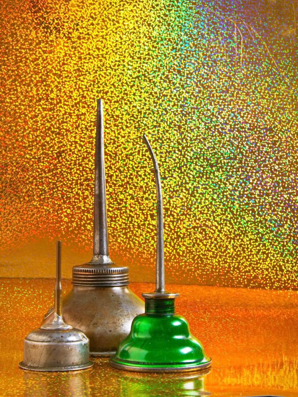 Free Image of Vintage oil cans against a vibrant orange background 