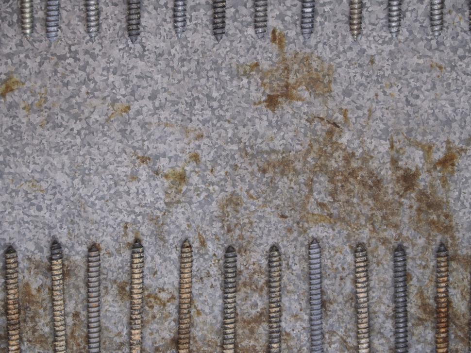 Free Image of Rusty bolts and screws lined up against a metal background. 