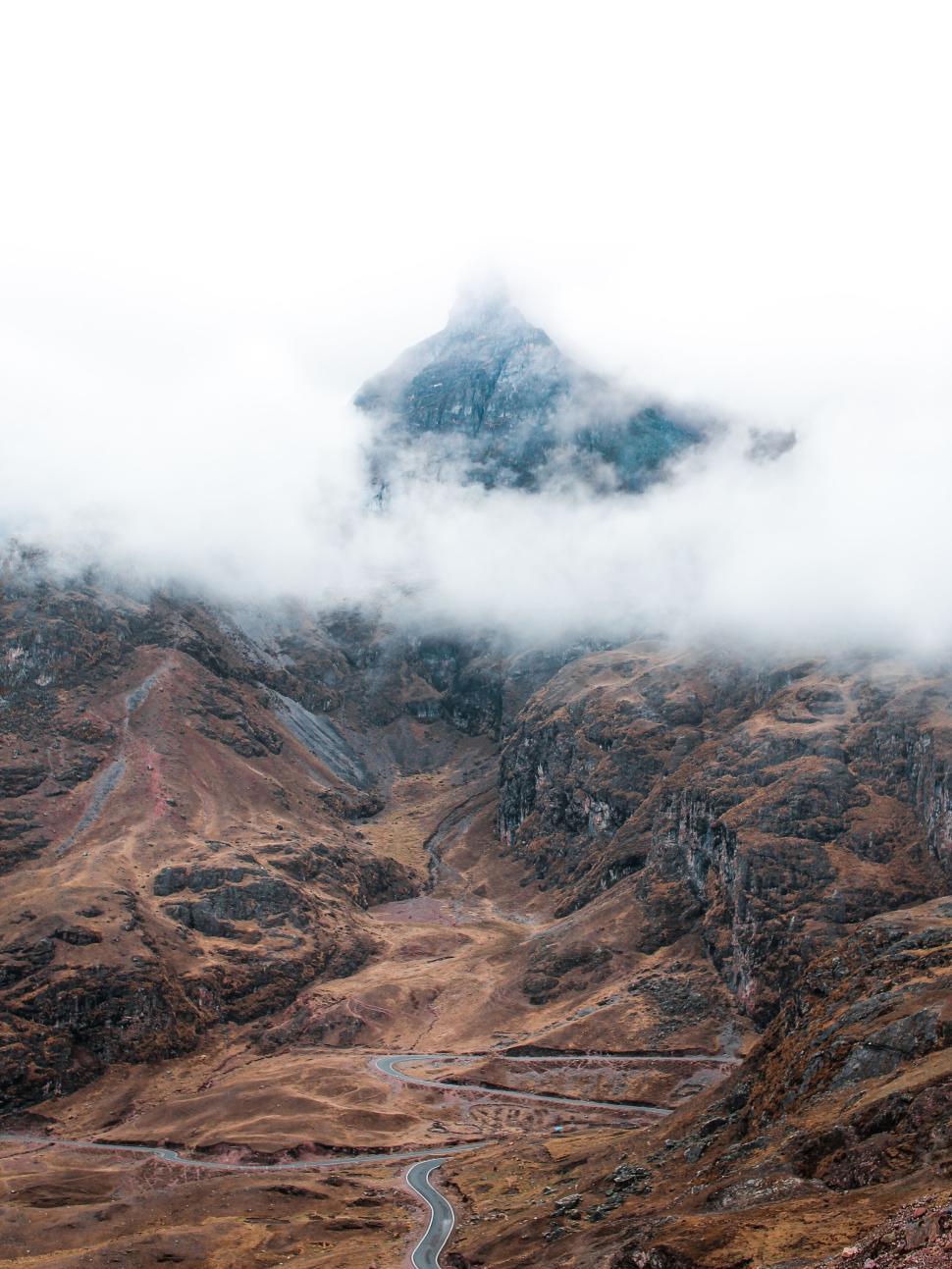 Free Image of Misty mountain peak emerging over rugged terrain 