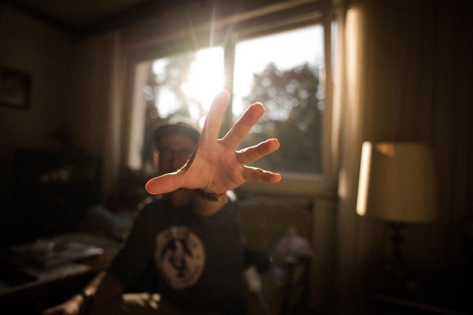 Free Image of Hand reaching towards sunlight in a peaceful indoor setting 