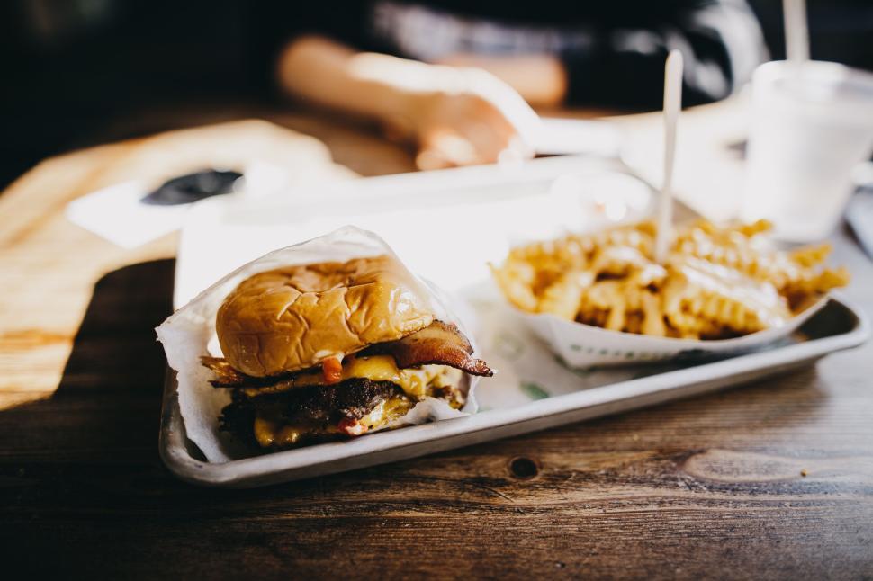 Free Image of Close-up of a juicy hamburger with crispy fries beside it 